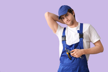 Tired male worker with wrench on lilac background - obrazy, fototapety, plakaty