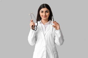 Obraz premium Beautiful young female doctor with syringe and stethoscope on white background