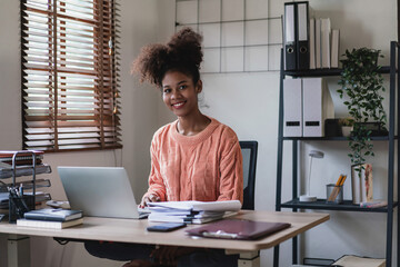 African american businesswoman looking at camera and smiling with happiness while working in office