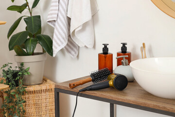 Round brush with hair dryer on table in bathroom, closeup