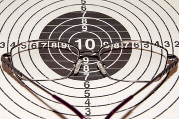 Signs and Symbols. Glasses lie on a shooting target