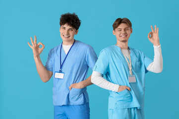 Male medical interns showing OK on blue background