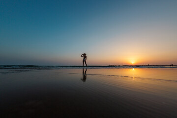 silhouette of a woman walking along the beach. Meditation of the spiritual world. Happy girl walks along the beach against the backdrop of sunset.