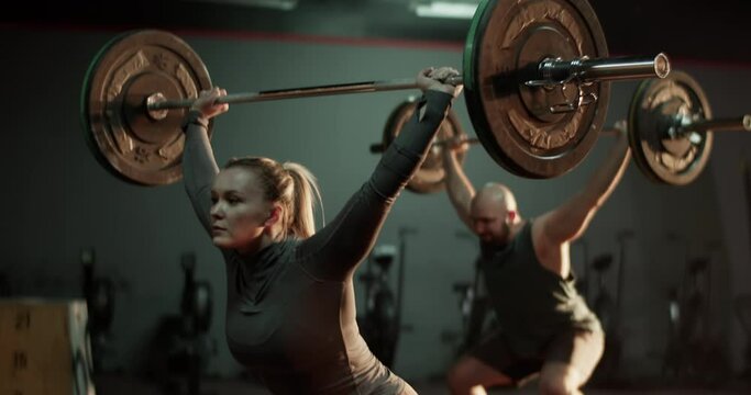 Coach and trainee training with barbell in gym