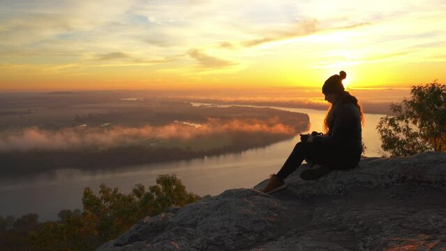 Girl Sits on Mountain With Beautiful Dramatic Sunset Autumn Fall Foliage Landscape in Background . Petit Jean Arkansas State Park Tourist Destination.