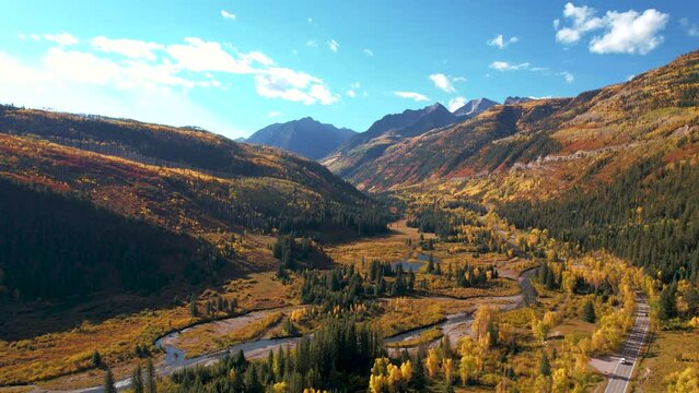 Aerial Colorado Epic Landscape Mountain Road in Autumn. Cars driving mountain path winding rivers yellow aspen trees forest