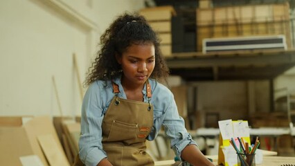 Professional carpenter or woodworker or charpentier woman check wood product on table then look at camera with smiling in workplace.