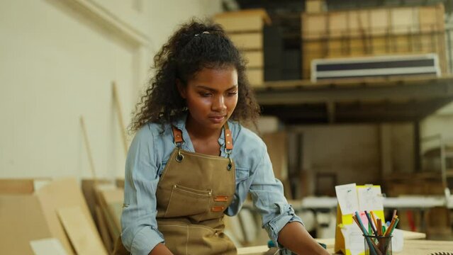 Professional carpenter or woodworker or charpentier woman check wood product on table then look at camera with smiling in workplace.