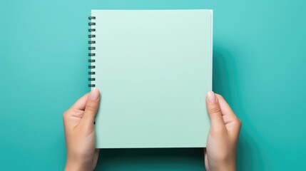 A clean notebook for notes is held by women's hands on a colored background, concepts of education, workplace, creativity. A place for text or advertising.