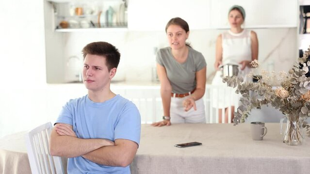 Rebellion of young guy. Woman and young girl swear at brother. Mom and older sister scold young guy for unsuccessful studies at university. Complex intergenerational relationships 