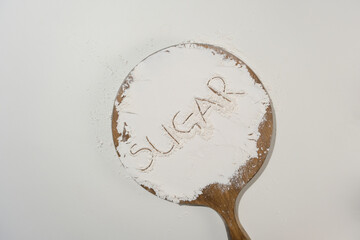 Minimalist cooking stylish with a wooden round chopping board has dough sprinkle on surface with a text “sugar”. Blank space for displaying product or adding text