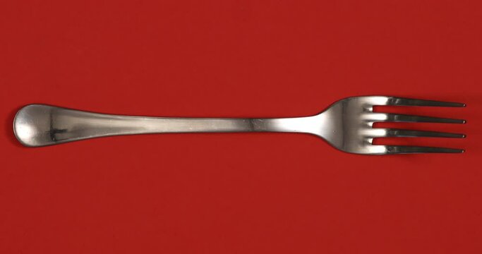 Cutlery stop motion animation. Different kinds of knives and forks changing on red background. 4K top view shot.