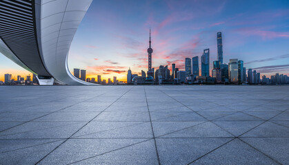 Empty square floor and pedestrian bridge with modern city buildings at dusk in Shanghai. Panoramic view.