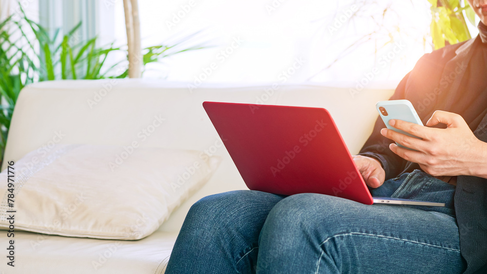 Poster a man sitting on the sofa and using a smartphone and laptop computer.