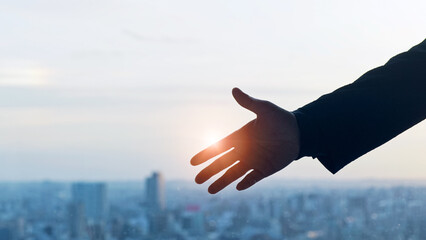 Silhouette of a man reaching out with a city background.