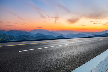 Asphalt highway road and mountains with sky clouds at dusk