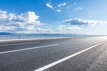 Asphalt highway road and mountains with sky clouds on a sunny day