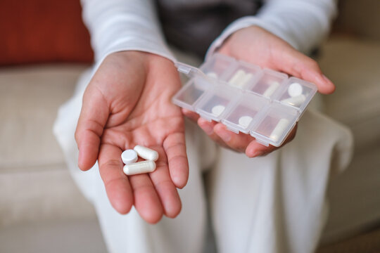 Closeup image of a woman holding pills and pillbox