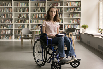 Portrait of attractive serious teenage student girl with mobility impairment posing for camera in...