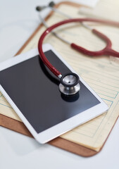 Hospital, clinic and tablet with stethoscope on desk for medical website, telehealth and research. Healthcare, cardiology and digital tech, equipment and clipboard for online consulting service