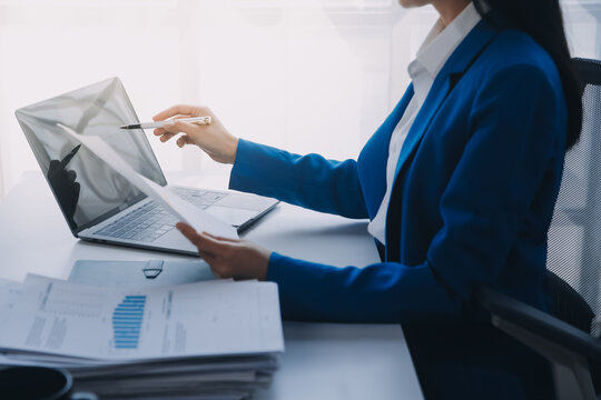 Cheerful business lady working on laptop in office, Asian happy beautiful businesswoman in formal suit work in workplace. Attractive female employee office worker smile.