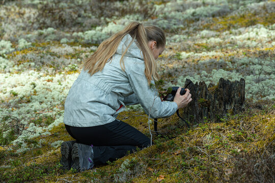 A woman takes a picture of forest nature with a camera