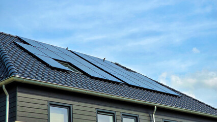 Fototapeta premium Newly build houses with solar panels attached on the roof against a sunny sky