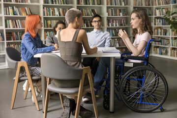 Group of diverse schoolmates listening team leader, girl with physical disability make speech...