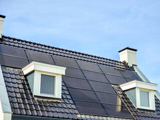 Fototapeta na wymiar house with black solar panels on the roof against a sunny sky Close up of new building with black solar panels. Zonnepanelen, Zonne energie, Translation: Solar panel, Sun Energy, energy transition