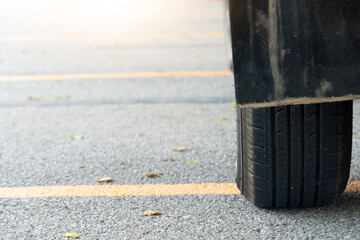 Close of used car tires on asphalt road with sun light in the morning time. With yellow line across...
