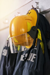Uniform, helmet and jacket of firefighter on wall for rescue, emergency service and protection. Fire brigade, safety gear and equipment, outfit and ppe on rack for health department in station