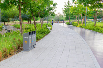 walking path with trash cans for collecting separate waste in a city park