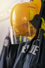 Uniform, helmet and clothes of firefighter on wall for rescue, emergency service and protection....