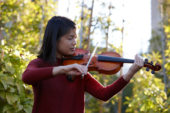 Young Asian female violin player practising outdoors