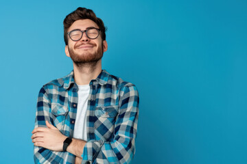 Fototapeta premium Portrait of a handsome young man in a glasses with a crossed arms in a studio plain background. AI generated