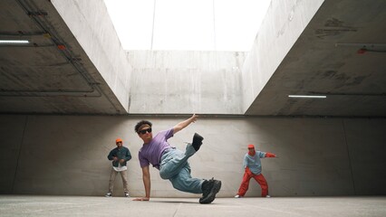 Group of stylish hipster perform dancing together in building. Happy break dancer enjoy moving to...