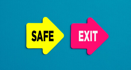 The word safe exit on arrow shaped stickers on blue background. Safe exit way in business concept.