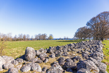 Big stone wall on a field in a rural landscape at springtime