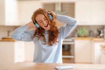 Cheerful young redhead woman  using a mobile phone, listening to favorite songs, audiobooks,...