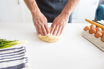 Man's hands kneading dough on the table in the kitchen