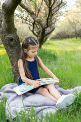 A child girl is reading a book in the park