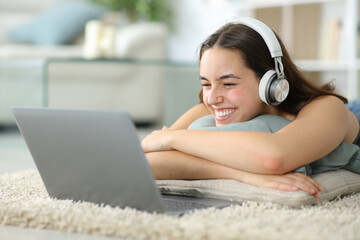Happy woman watching media content on laptop at home - 785030300