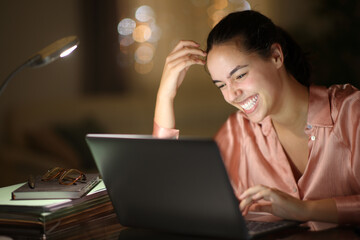 Tele worker in the night laughing checking laptop