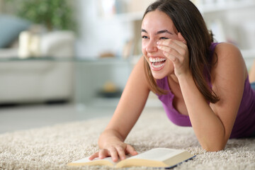 Happy woman laughing hilariously reading a comedy paper book