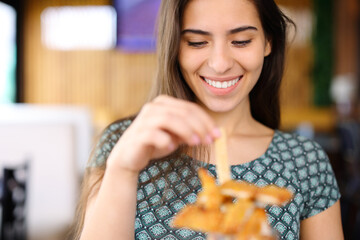 Happy woman eating chicken fingers in a restaurant