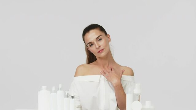 Advertising of spa treatments, anti-aging care products for delicate dry skin. Portrait of an attractive middle-aged woman next to mock-ups of jars of cream and cosmetology natural cosmetics.