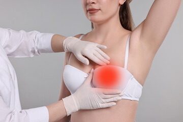 Mammologist checking woman's breast on gray background, closeup
