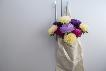 Mixed colorful flowers in cotton bag on door knob. Creative minimalistic flowers. Concept of holiday celebrating present and gift. Bouquet delivery