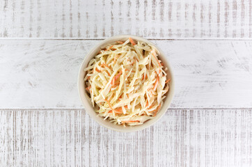 Classic coleslaw salad made with fresh cabbage, carrots and dressing on a white background. American cuisine. Top view.