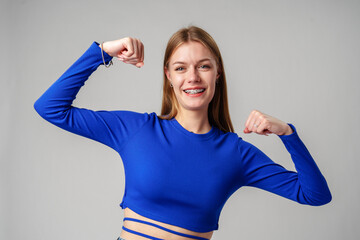 Smiling Young Woman in Blue Top Celebrating Success With Raised Fist